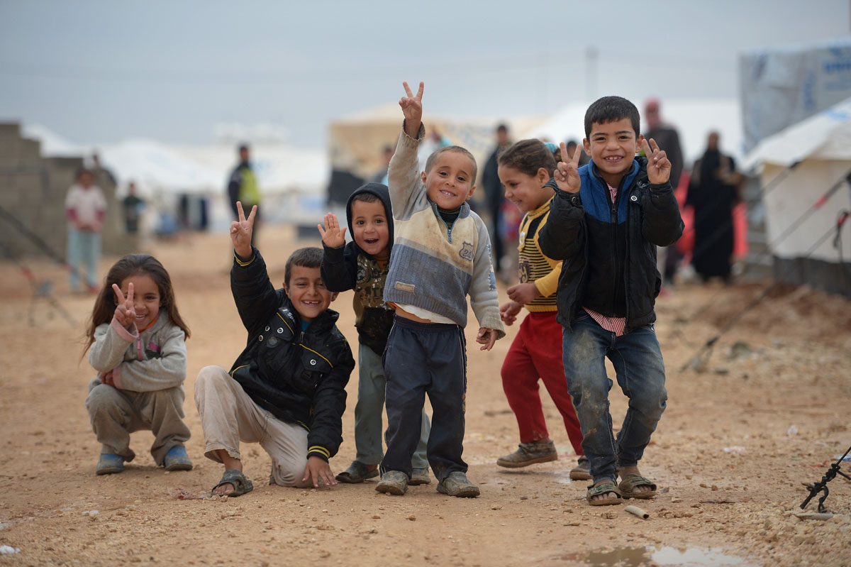 ZA'ATARI, JORDAN - FEBRUARY 01:  Children pose for a picture as Syrian refugees go about their daily business in the Za'atari refugee camp on February 1, 2013 in Za'atari, Jordan. Record numbers of refugees are fleeing the violence and bombings in Syria to cross the borders to safety in northern Jordan and overwhelming the Za'atari camp. The Jordanian government are appealing for help with the influx of refugees as they struggle to cope with the sheer numbers arriving in the country.  (Photo by Jeff J Mitchell/Getty Images) ORG XMIT: 160600686