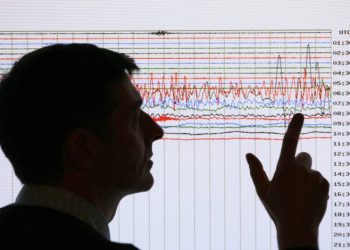 A seismologist poses for the media as he points to a seismographic graph showing the magnitude of the earthquake in Japan, on a monitor at the British Geological Survey office in Edinburgh, Scotland March 11, 2011. The biggest earthquake on record to hit Japan struck the northeast coast on Friday, triggering a 10-metre tsunami that swept away everything in its path, including houses, ships, cars and farm buildings.    REUTERS/David Moir (BRITAIN - Tags: DISASTER ENVIRONMENT) - RTR2JR7P